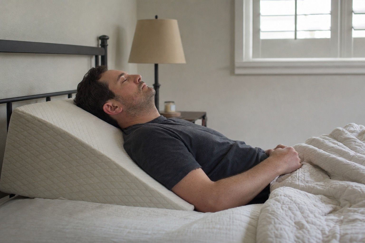A person asleep with their upper body raised on a foam wedge pillow so the torso is gently inclined